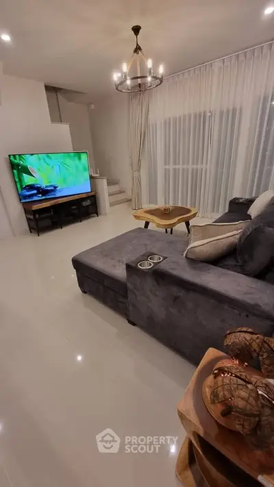Modern living room with sleek furniture and large TV, perfect for relaxation and entertainment.