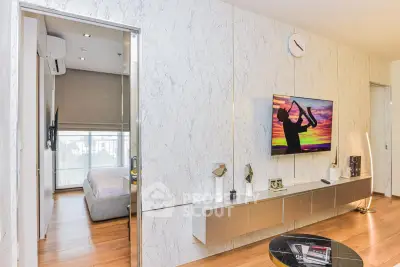 Modern living room with stylish decor and wall-mounted TV, featuring a glimpse into a cozy bedroom.