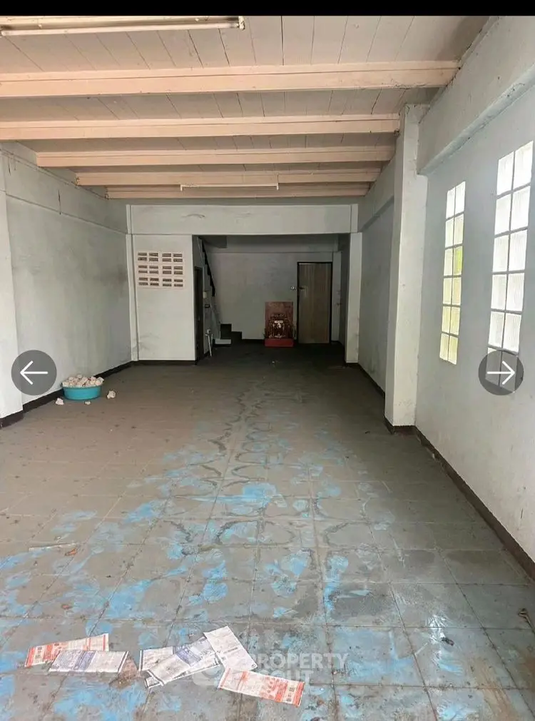 Spacious empty room with tiled floor and large windows, ideal for customization.