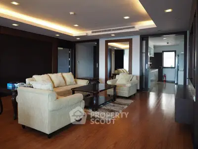 Spacious living room with elegant furniture and open kitchen layout in modern apartment.