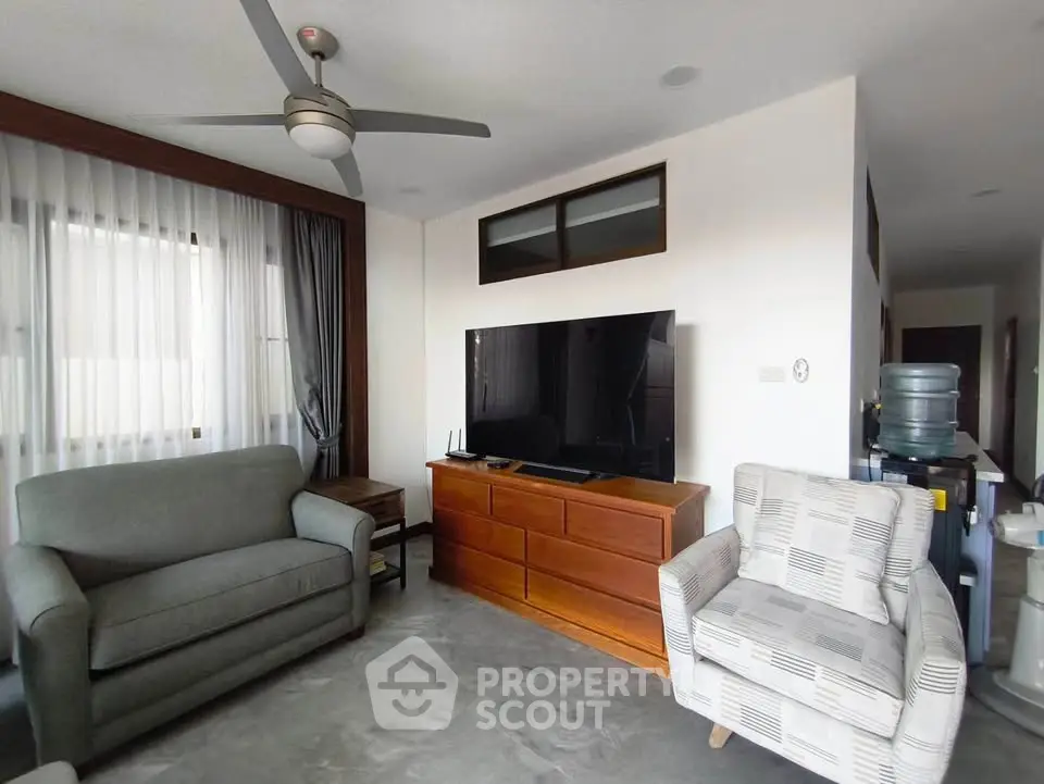 Spacious living room with modern furniture and large TV, perfect for relaxation.
