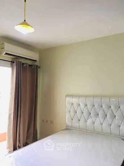Cozy bedroom with elegant tufted headboard and air conditioning, perfect for restful nights.