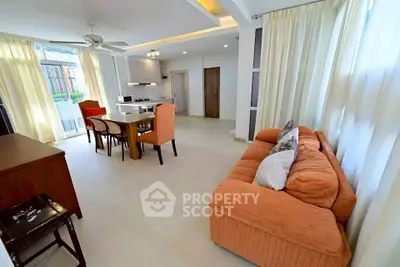 Spacious living room with open kitchen and stylish orange sofa, ideal for modern living.