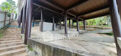 Unique elevated structure with open undercroft and wooden pillars in a serene natural setting.