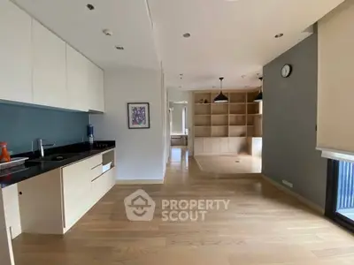 Spacious modern kitchen with open layout and wooden flooring, featuring sleek cabinetry and ample natural light.