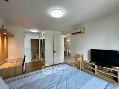 Spacious bedroom with modern furnishings and ample natural light, featuring a built-in wardrobe and air conditioning.