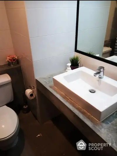 Modern bathroom with sleek white fixtures, marble countertop, and large mirror creating a spacious feel in a compact design, ideal for urban living.