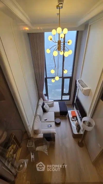 Luxurious high-ceiling living room with modern chandelier and panoramic city view.