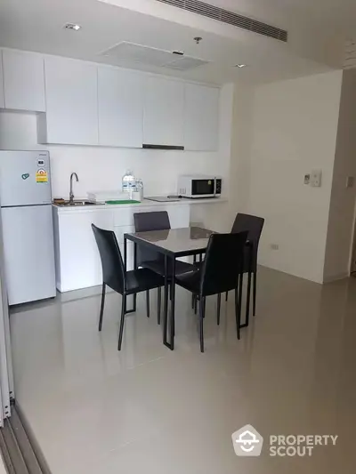 Modern kitchen with sleek dining area and appliances in a stylish apartment.