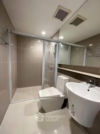 Modern bathroom with sleek fixtures and glass shower enclosure in a contemporary apartment.