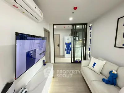 Modern living room with stylish decor and large TV, featuring a cozy sofa and air conditioning.