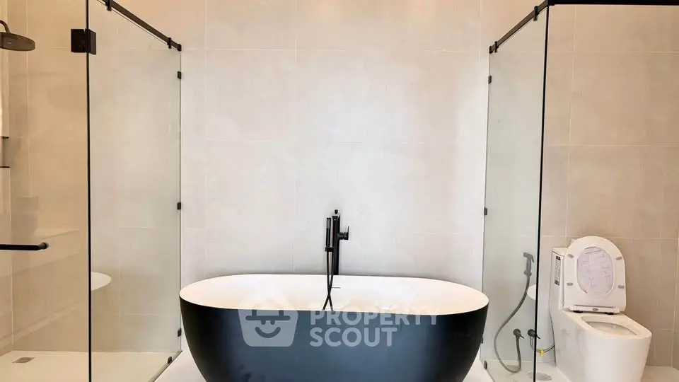 Luxurious modern bathroom with freestanding black bathtub and glass shower enclosure.