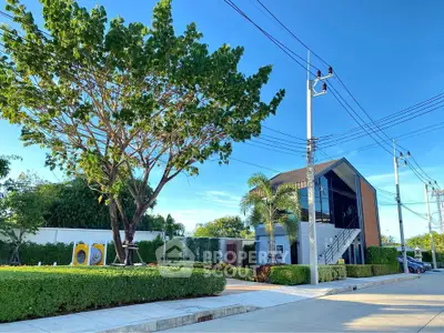 Modern two-story building with lush greenery and clear blue sky
