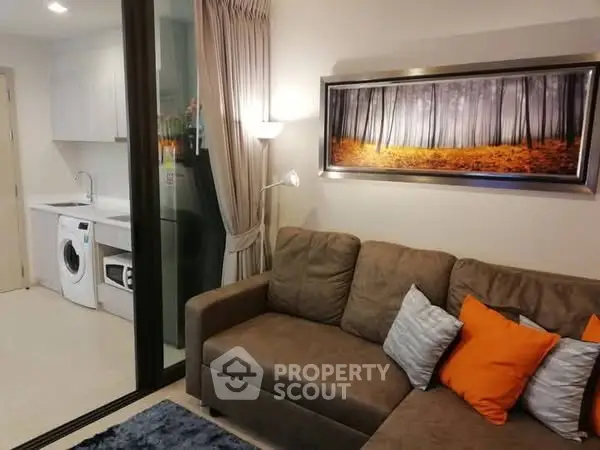 Modern living room with cozy sofa and stylish kitchen featuring washing machine.