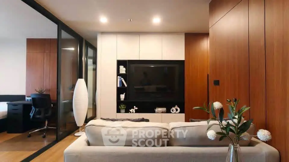 Modern living room with sleek design and cozy ambiance, featuring a large TV and stylish decor.