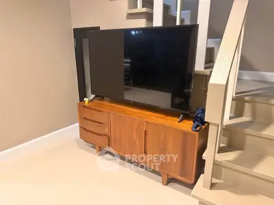 Stylish living room with modern TV stand and staircase, perfect for contemporary homes.