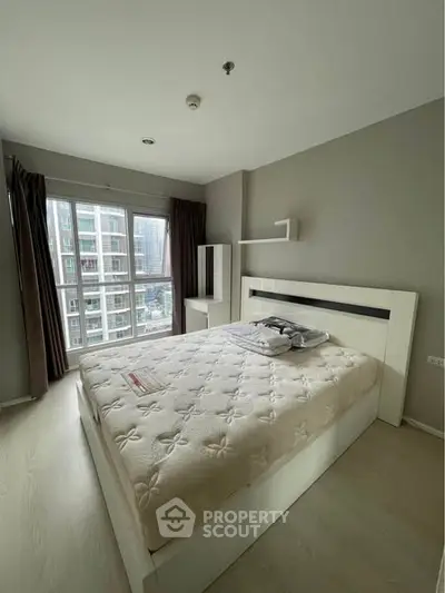 Modern bedroom with large window and city view in high-rise apartment