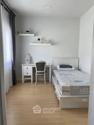 Cozy bedroom with single bed, desk, and shelves in a bright, minimalist design.