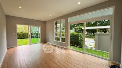 Spacious living room with large windows and garden view in modern home.