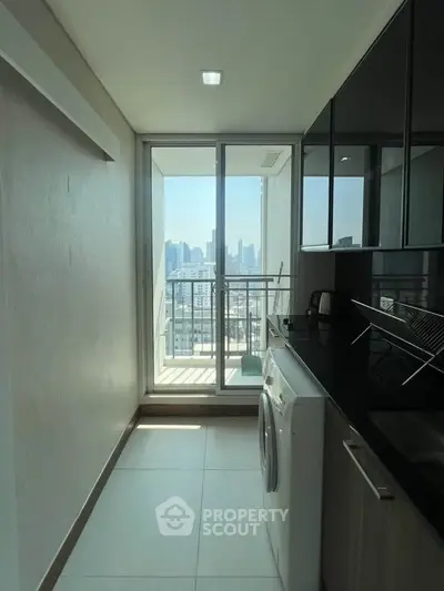 Modern kitchen with city view and balcony access, featuring sleek cabinetry and built-in appliances.