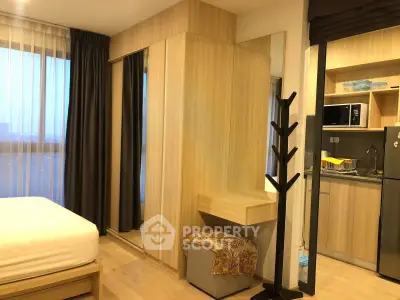 Modern studio apartment with cozy bedroom and compact kitchen area, featuring stylish wooden decor and ample natural light.