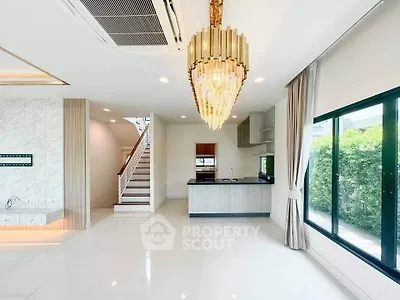 Luxurious open-plan living room with elegant chandelier and modern kitchen in a bright, spacious home.