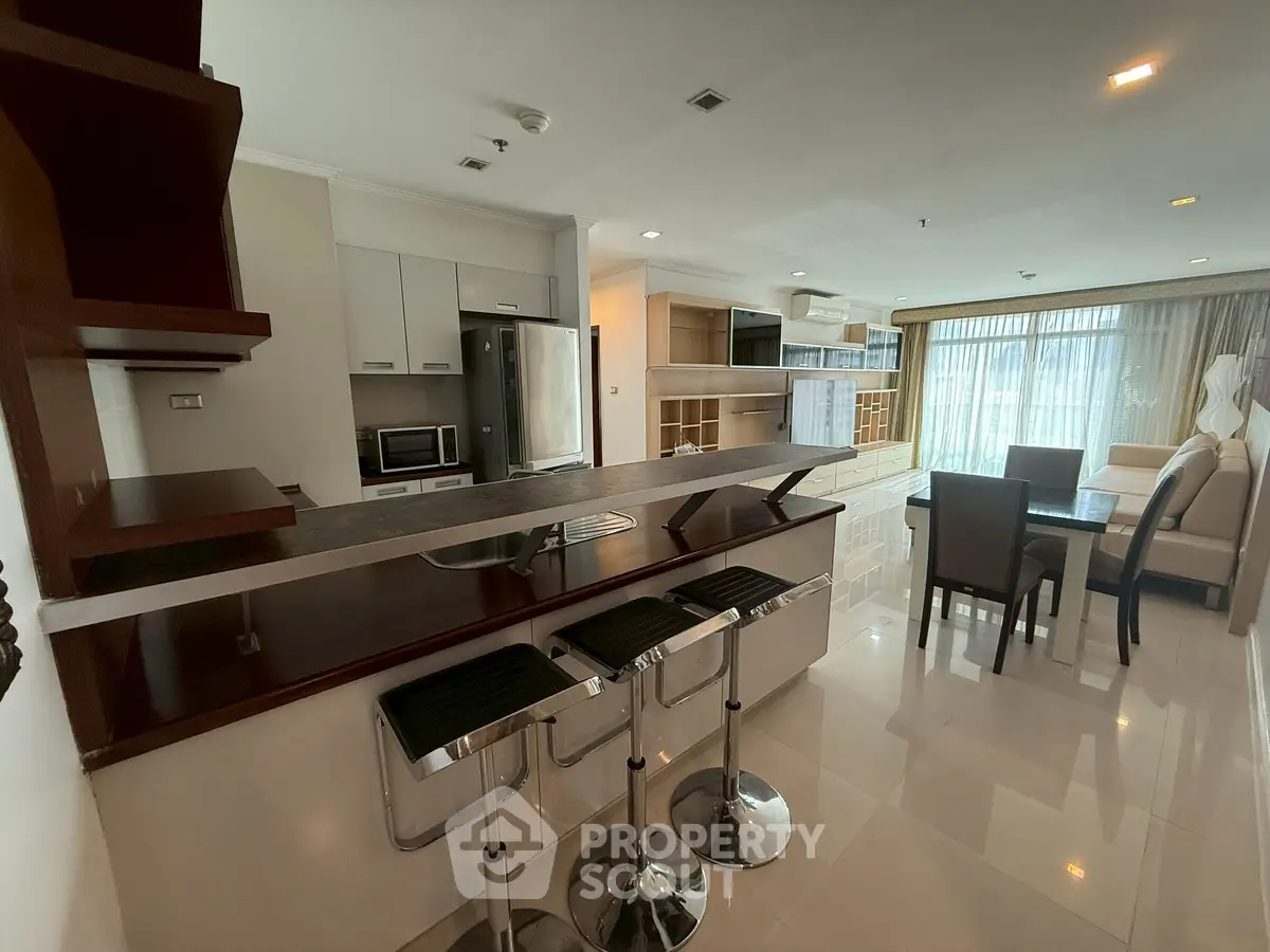 Spacious modern living area with open kitchen and dining space, featuring sleek furnishings and ample natural light.