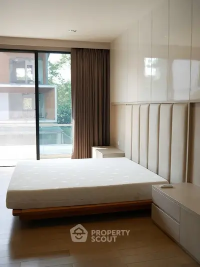 Modern bedroom with large window and elegant furnishings in a luxury apartment.