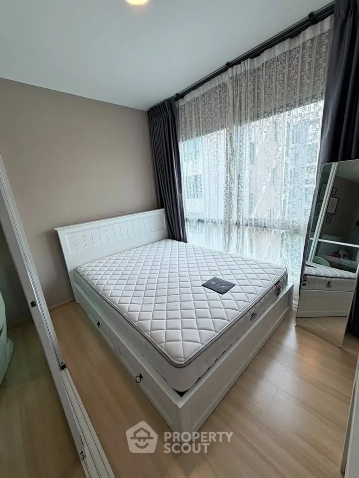 Spacious bedroom with large window and elegant curtains, featuring a comfortable bed and stylish decor.