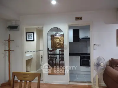 Cozy living space with modern kitchen and bathroom access, featuring stylish decor and wooden accents.