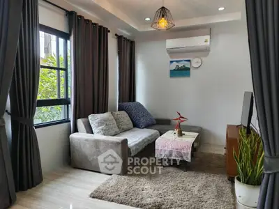 Cozy living room with modern decor, featuring a comfortable sofa, air conditioning, and natural light.