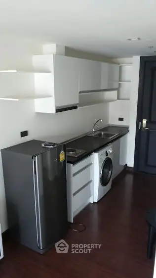 Modern compact kitchen with sleek appliances and dark wood flooring