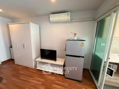 Modern living room with air conditioning, TV, and fridge in a cozy apartment setting.