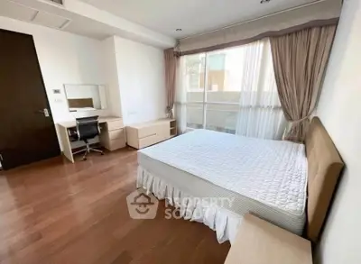 Spacious bedroom with modern furniture and large window for natural light.