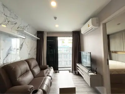 Modern living room with leather sofa, TV, and balcony access in stylish apartment.