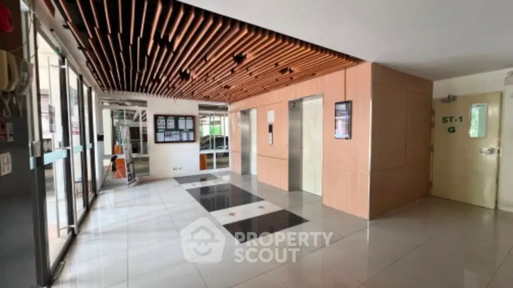 Modern building entrance with elevators and stylish ceiling design.