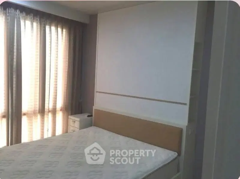 Spacious bedroom with large windows and natural light in modern apartment.