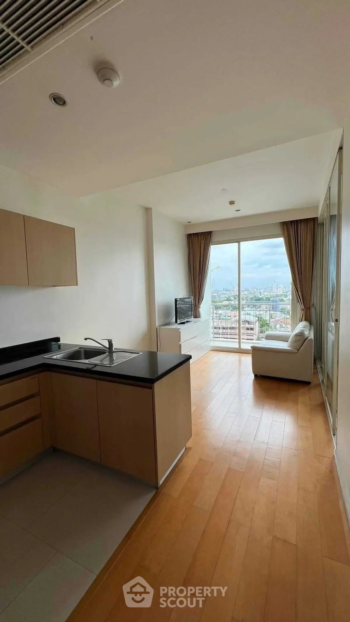 Modern open-plan living room with kitchen and city view balcony