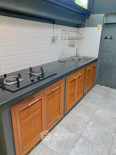 Modern kitchen with sleek gas stove and stylish cabinetry in open layout.