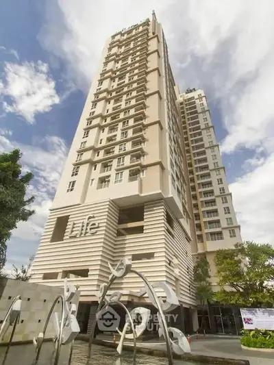 Stunning high-rise building with modern architecture and artistic entrance in vibrant urban setting.
