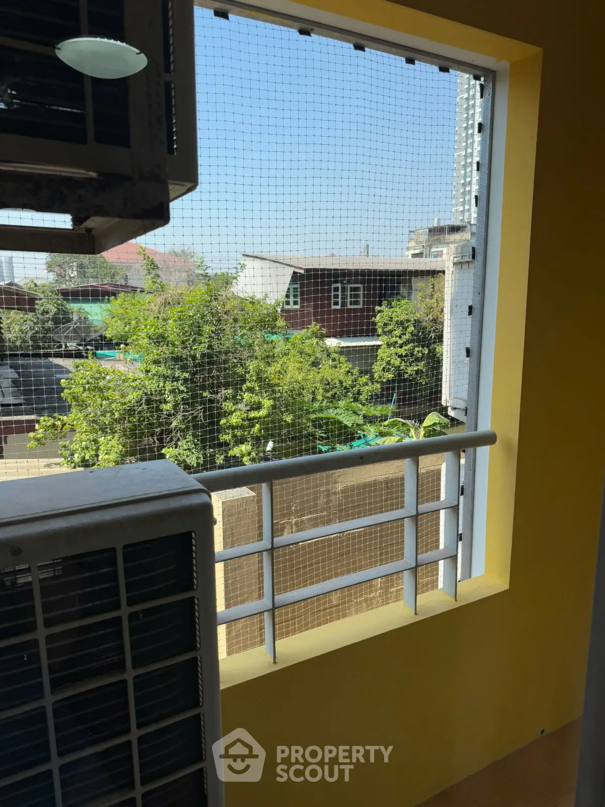 Charming balcony view with lush greenery and urban backdrop, perfect for relaxation and city living.