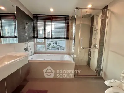 Luxurious bathroom with city view, featuring a bathtub and glass shower enclosure.