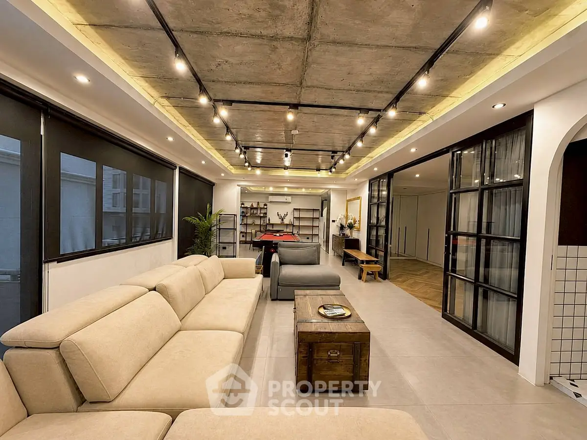 Spacious modern living room with industrial ceiling and cozy beige sofa