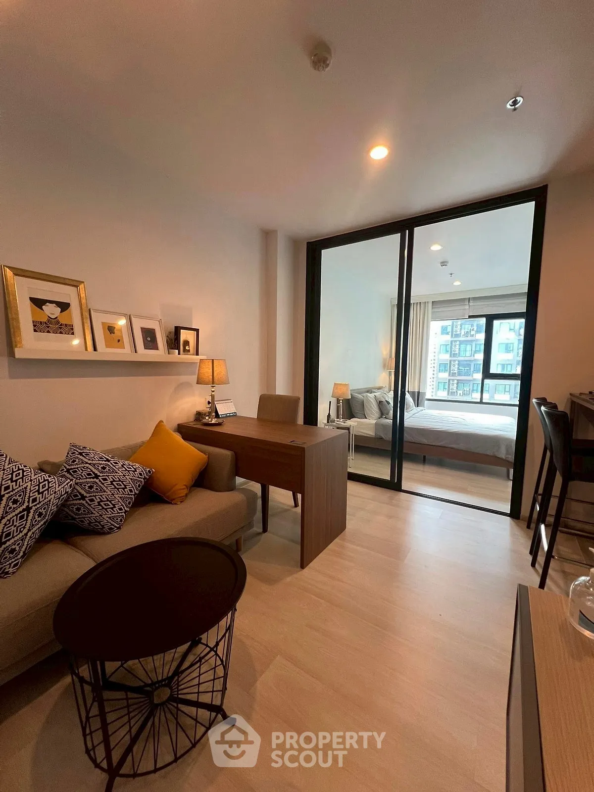 Modern living room with cozy sofa and stylish decor leading to a bright bedroom.