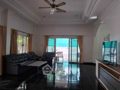 Spacious living room with elegant ceiling design and large windows opening to a patio.