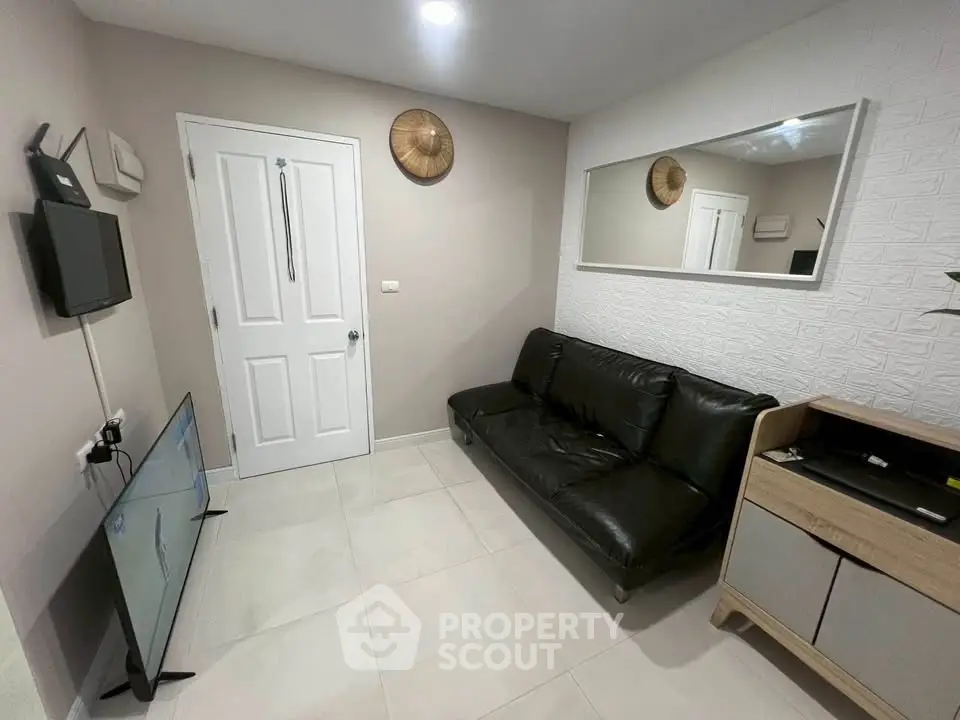 Cozy living room with modern decor, featuring a sleek black sofa, wall-mounted TV, and stylish mirror.