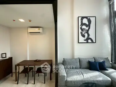 Modern living room with stylish furniture and wall art, featuring a cozy gray sofa and dining area.