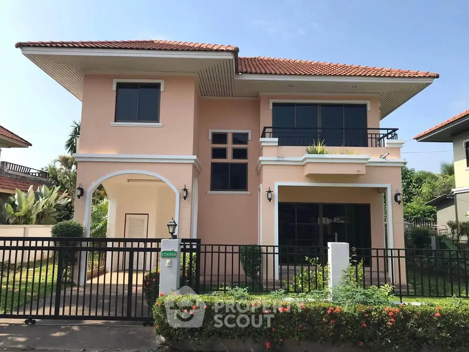 Charming two-story house with red-tiled roof and lush garden in a serene neighborhood.