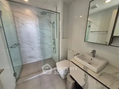 Modern bathroom with glass shower and marble accents in luxury apartment
