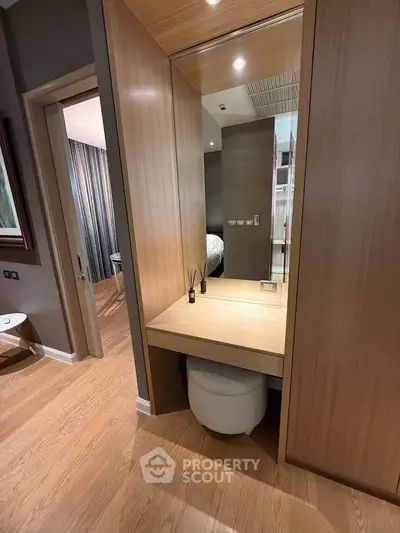 Modern bedroom with elegant wooden vanity and stool, showcasing sophisticated interior design.